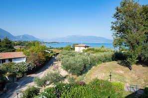 A residential area with a view of the sea, a small building, and surrounding greenery. - Residence Atollo (Manerba del Garda)