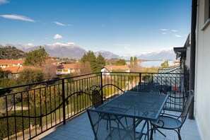 Ein Balkon mit Tisch und Stühlen mit Blick auf einen See und Berge.