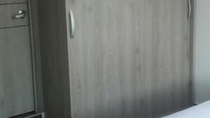 A bedroom with a bed, a wardrobe, and a door. - Lindo Apartamento (Ricaurte)