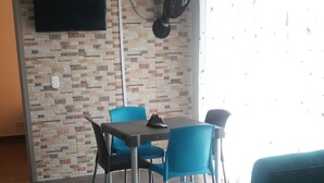 A modern living room with a dining area, a flat-screen TV mounted on a textured wall, and a ceiling fan. - Lindo Apartamento (Ricaurte)