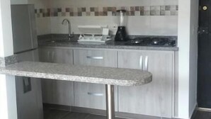 A modern kitchen with grey cabinets, a stainless steel countertop, and a black range hood. - Lindo Apartamento (Ricaurte)