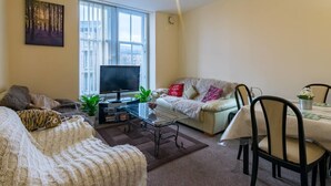 A living room with a sofa, a coffee table, a TV, and a dining area with chairs and a table. - Heart of Finnieston (Glasgow)