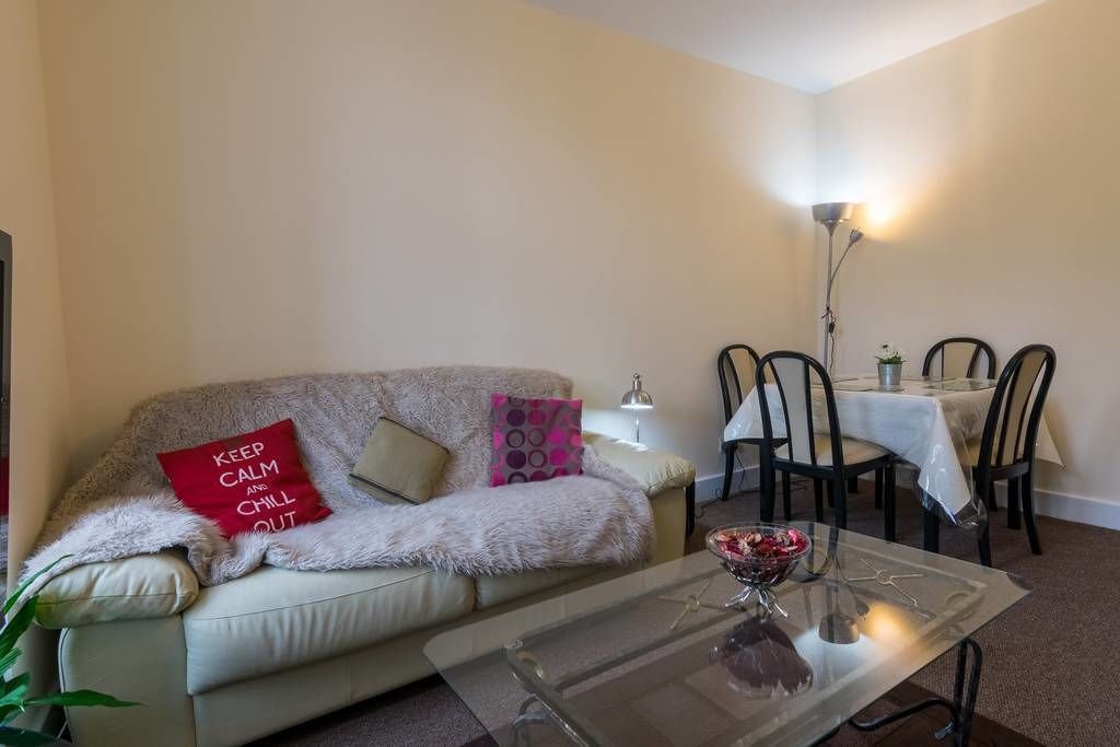 Ein gemütliches Wohnzimmer mit einer Couch, einem Glastisch und einem Essbereich mit Stühlen und Tisch.
