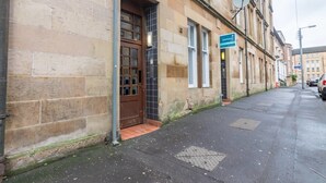 A building with a stone facade, a brown door, and a blue sign indicating a business. - Heart of Finnieston (Glasgow)