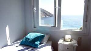 A bedroom with a bed, a window with a view of the sea, and a bedside table with a candle. - Spectacular Frontline Apt Sea Views 2mins Walk to Beach /5mins to Moraira (Moraira)