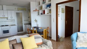 A living room with a sofa, a blue armchair, and a dining area with a table and chairs. - Spectacular Frontline Apt Sea Views 2mins Walk to Beach /5mins to Moraira (Moraira)