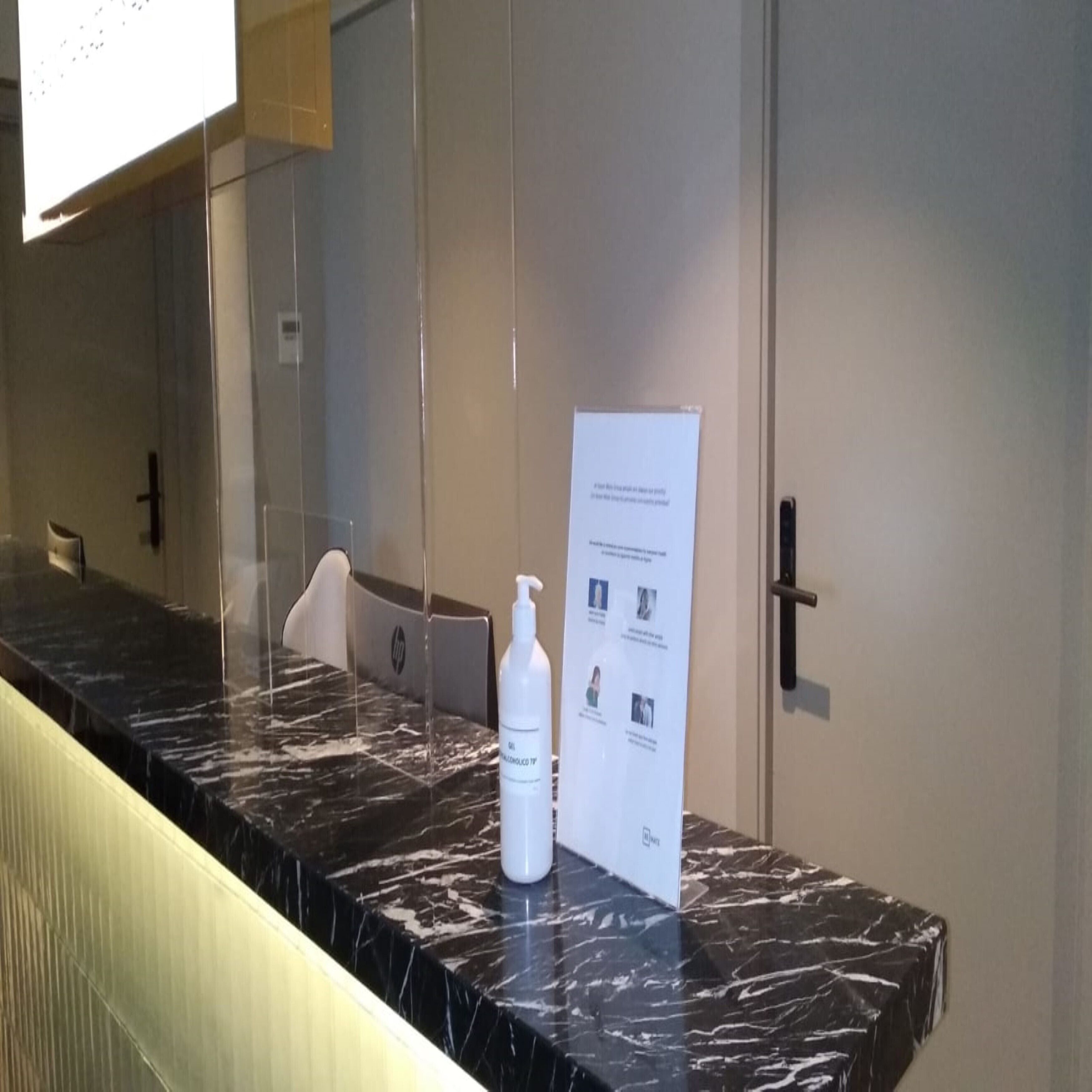 Un baño con encimera de mármol, una botella blanca y un cartel con texto.