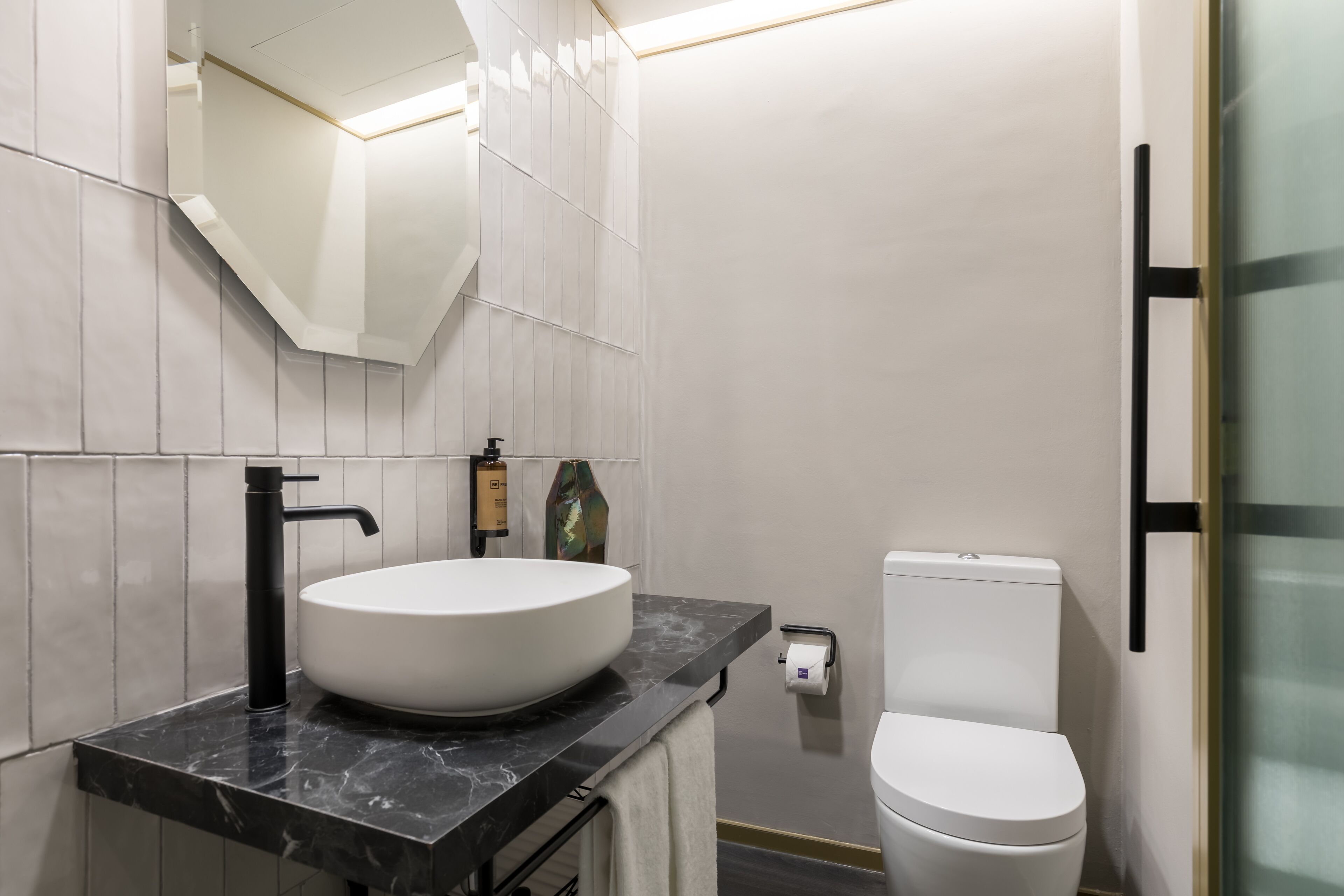 A modern bathroom with a white sink, black faucet, and a toilet.