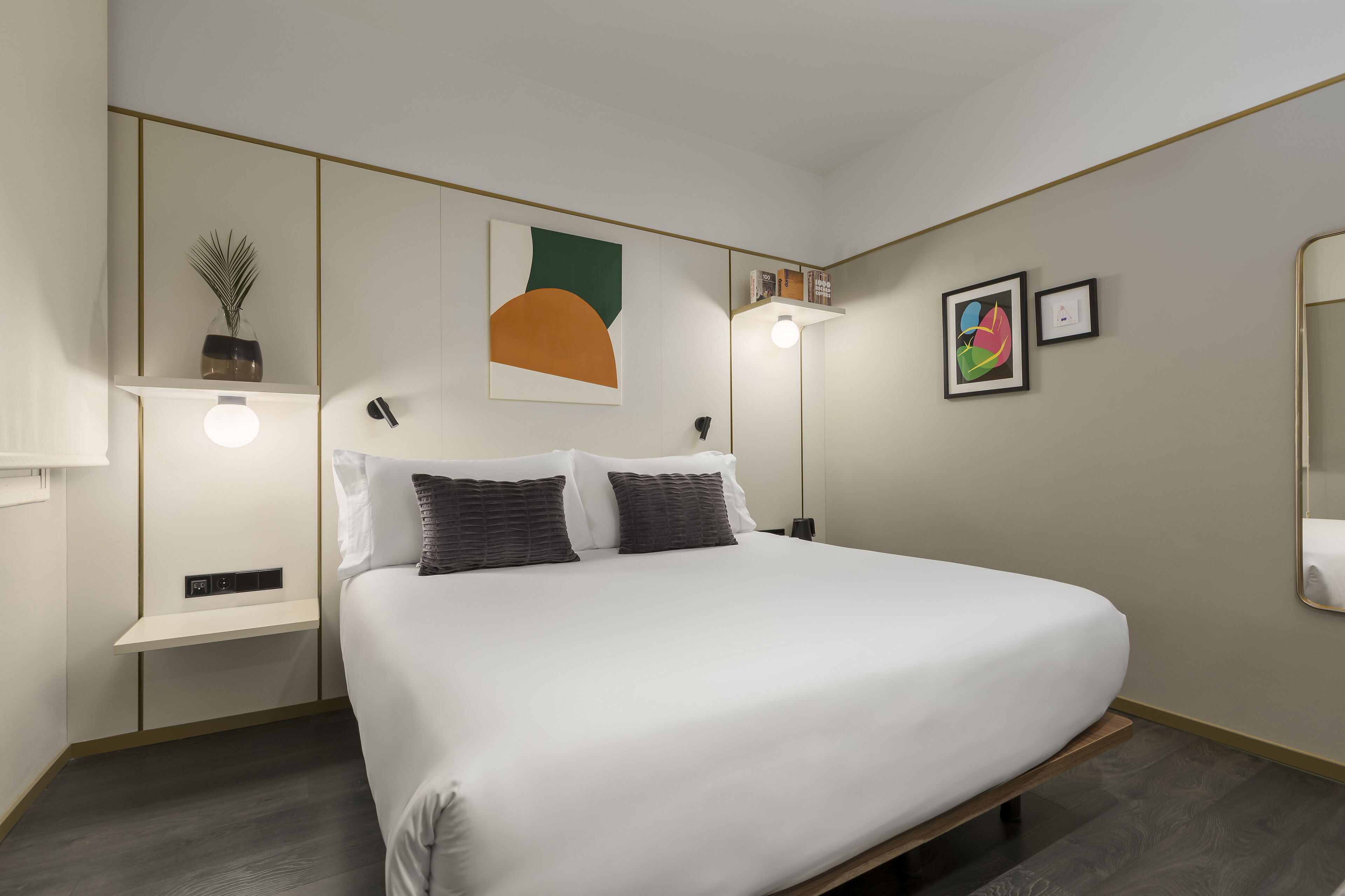 Una camera da letto moderna con un letto grande, comodini, una mensola a parete con una pianta e un grande specchio.