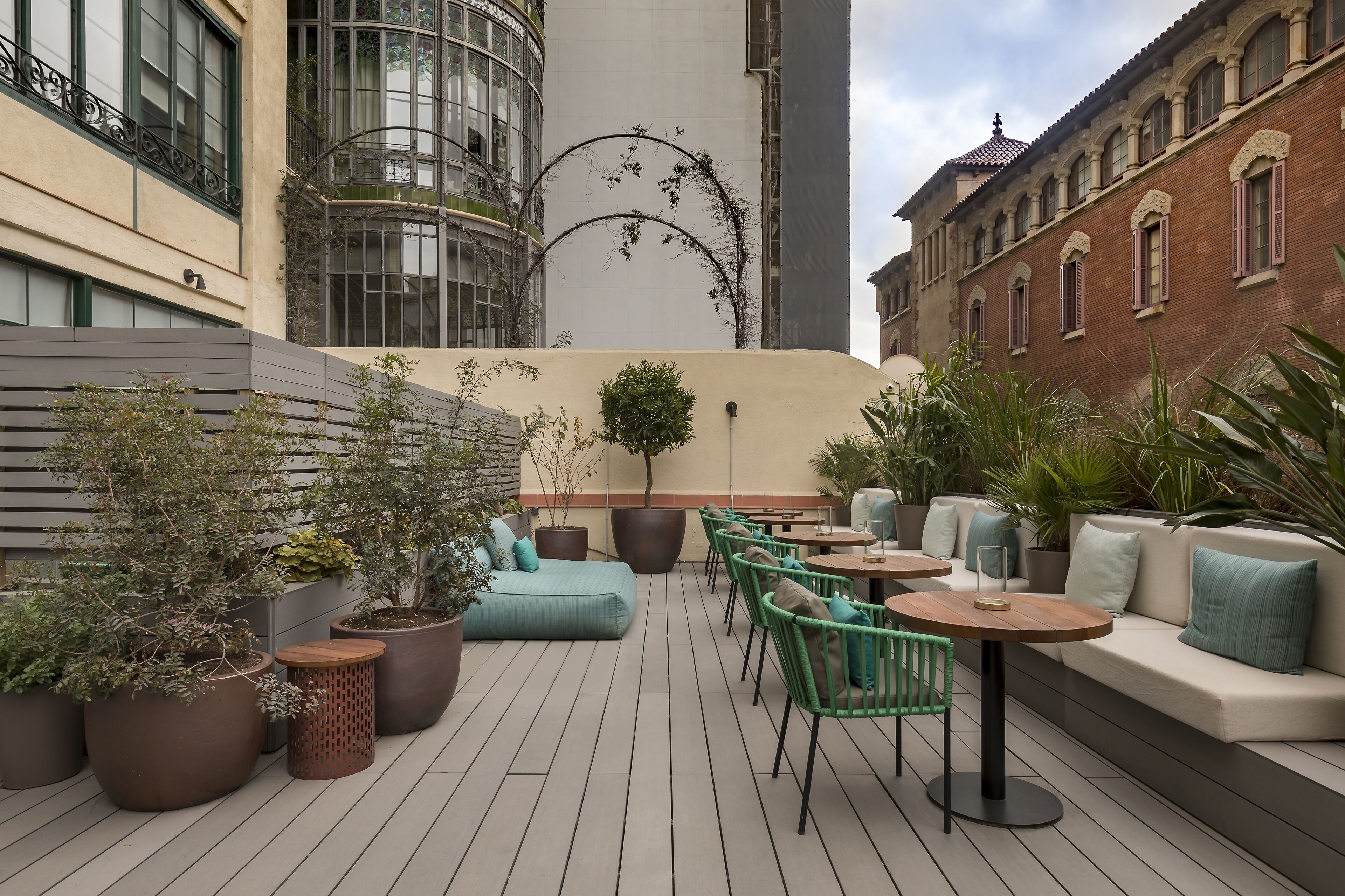 An outdoor patio with seating, potted plants, and a view of surrounding buildings.