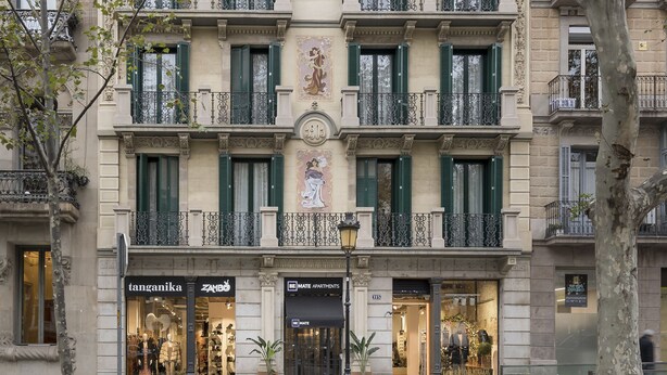 Un edificio de varios pisos con balcones, escaparates y vista a la calle.