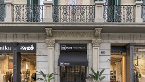 Fachada de edificio con locales comerciales, incluyendo una boutique y una planta en maceta.