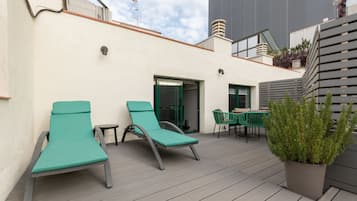 Una terraza en la azotea con dos sillones de descanso, una mesa y una planta en maceta.