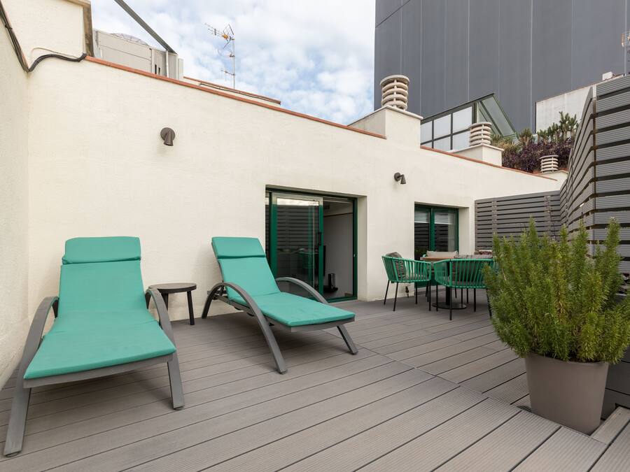 Una terraza en la azotea con dos sillones de descanso, una mesa y una planta en maceta.