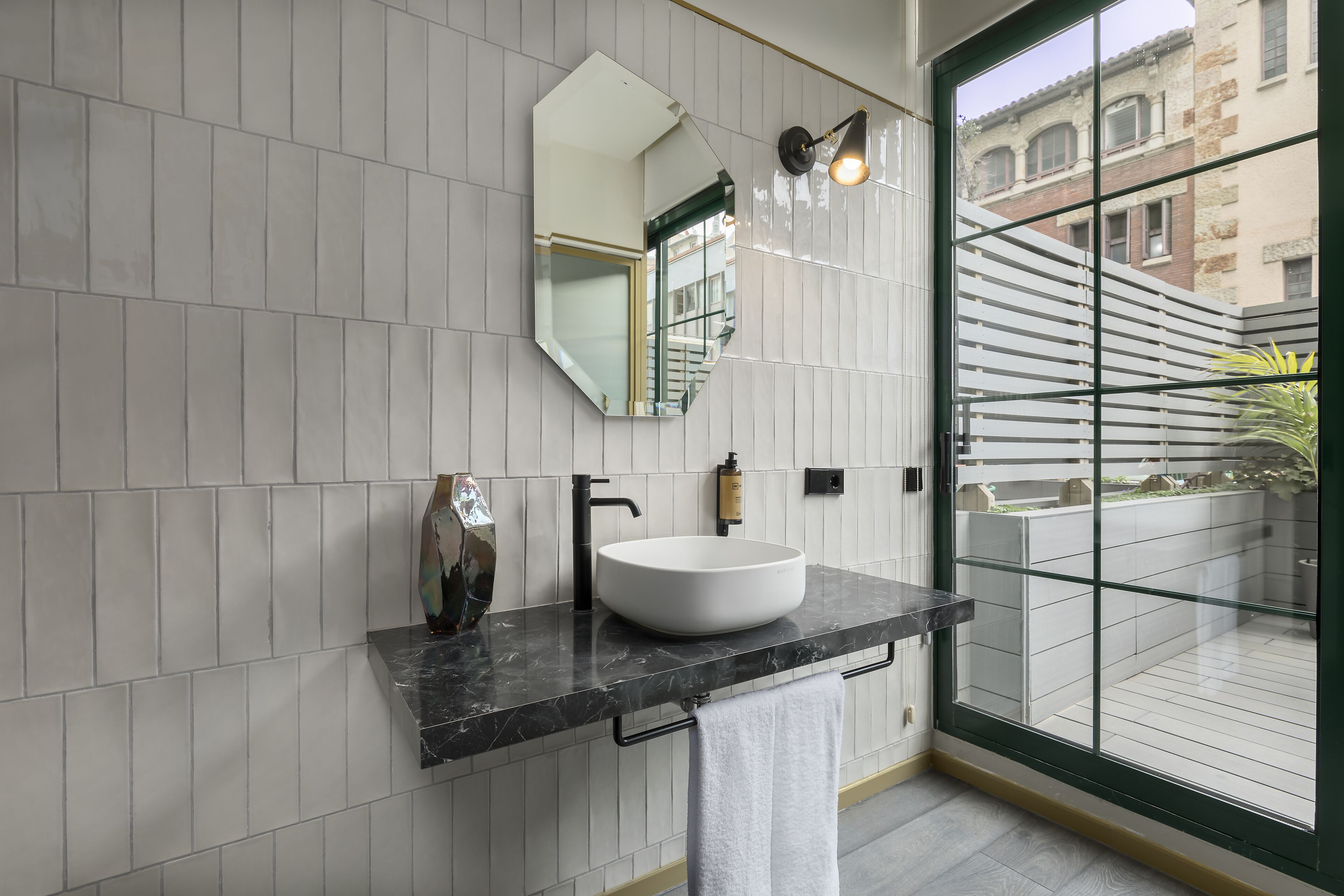 Een moderne badkamer met een witte wastafel, een zwart aanrechtblad en een grote spiegel.
