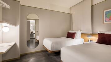 Habitación de hotel con dos camas, un escritorio, un espejo y una lámpara.