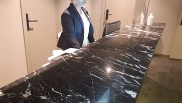 Un mostrador de recepción de mármol en el vestíbulo de un hotel, con un letrero que indica los números de habitación 01-02.