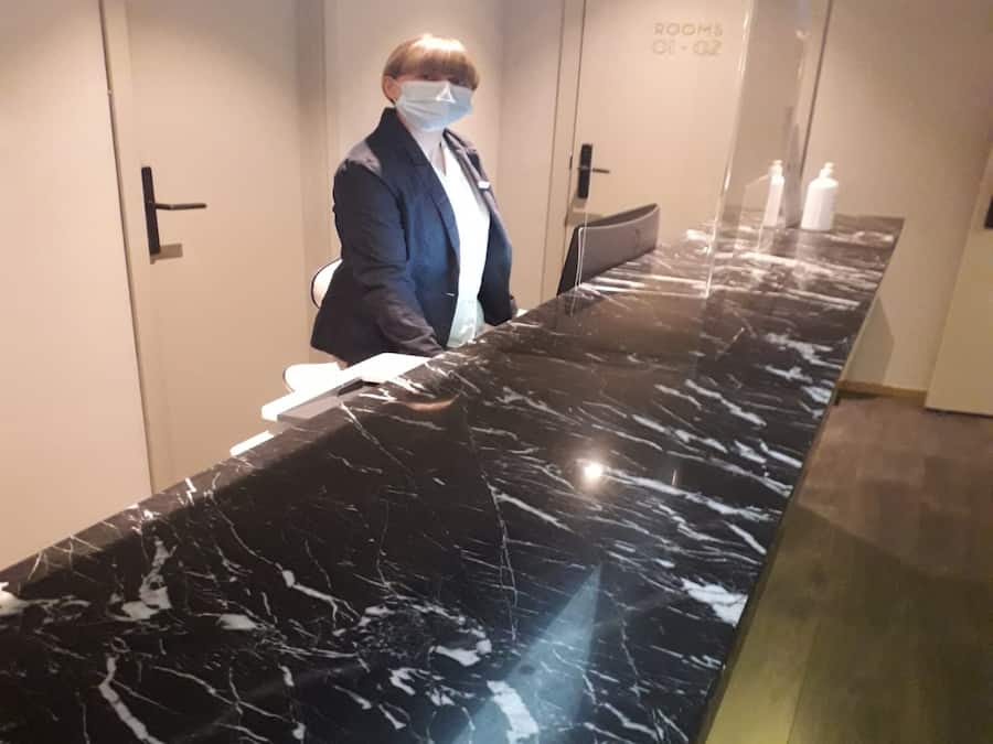 Un mostrador de recepción de mármol en el vestíbulo de un hotel, con un letrero que indica los números de habitación 01-02.