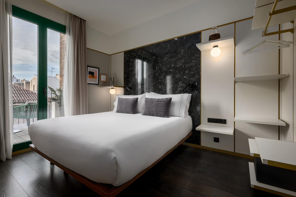 Ein modernes Hotelzimmer mit einem großen Bett, einem Marmorkopfbrett, Blick auf die Stadt und einem minimalistischen Design.