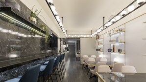 Un restaurante moderno con barra de mármol, sillas azules y una larga mesa de comedor.