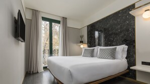 Un dormitorio moderno con cama, televisor montado en la pared y ventana con cortinas.