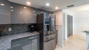 A modern kitchen with a stainless steel refrigerator, a coffee maker, and a tiled backsplash. - Spectacular Gulf views- South Seas Tower 4-1607 (Marco Island)