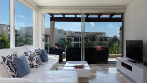 A modern living room with a white sofa, black and white patterned pillows, a coffee table, and a flat-screen TV. - Incredible 3 bedroom Penthouse at The Elements by BRIC (Playa del Carmen)