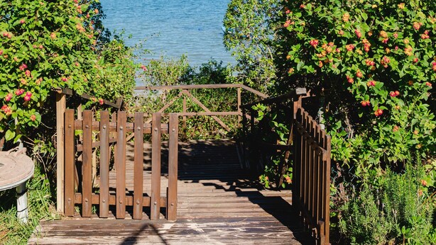 Un sendero de madera que lleva a una puerta con vista al mar.