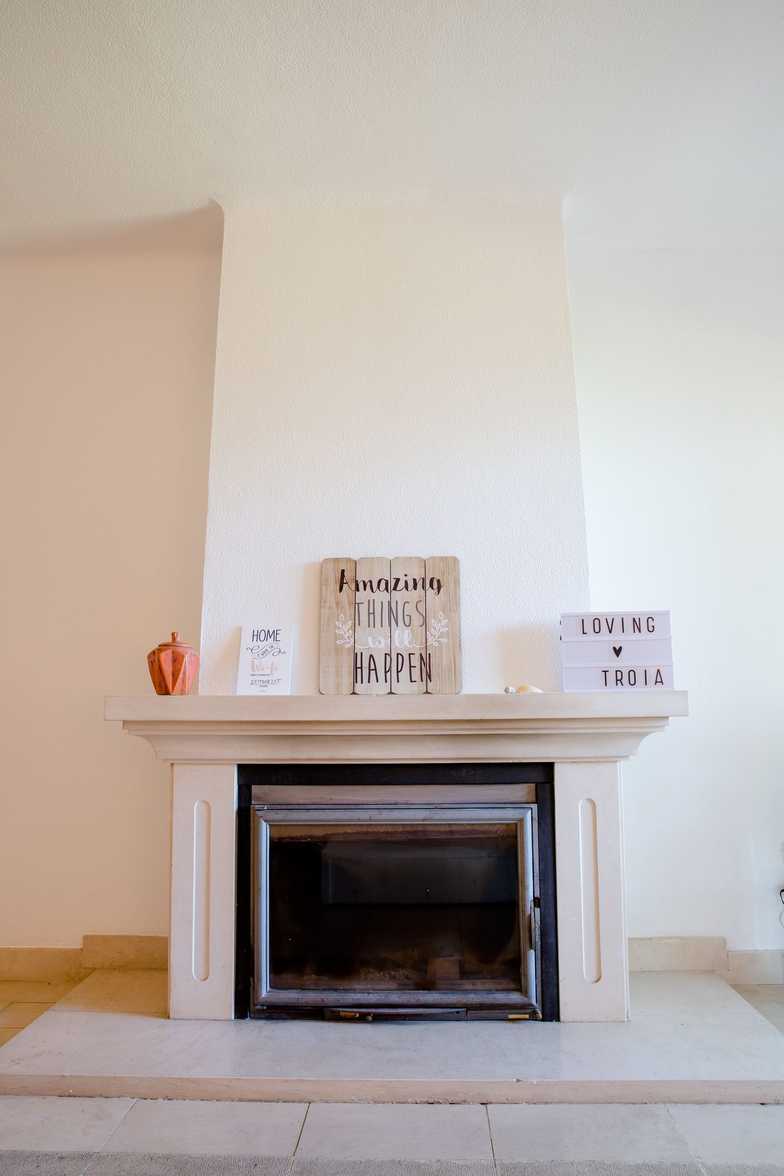 Una chimenea con un repisa que muestra letreros que dicen "Amazing Things Happened Here" y "Loving Troia".