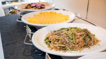 A buffet table with various dishes including a plate of mixed vegetables and shredded cheese.