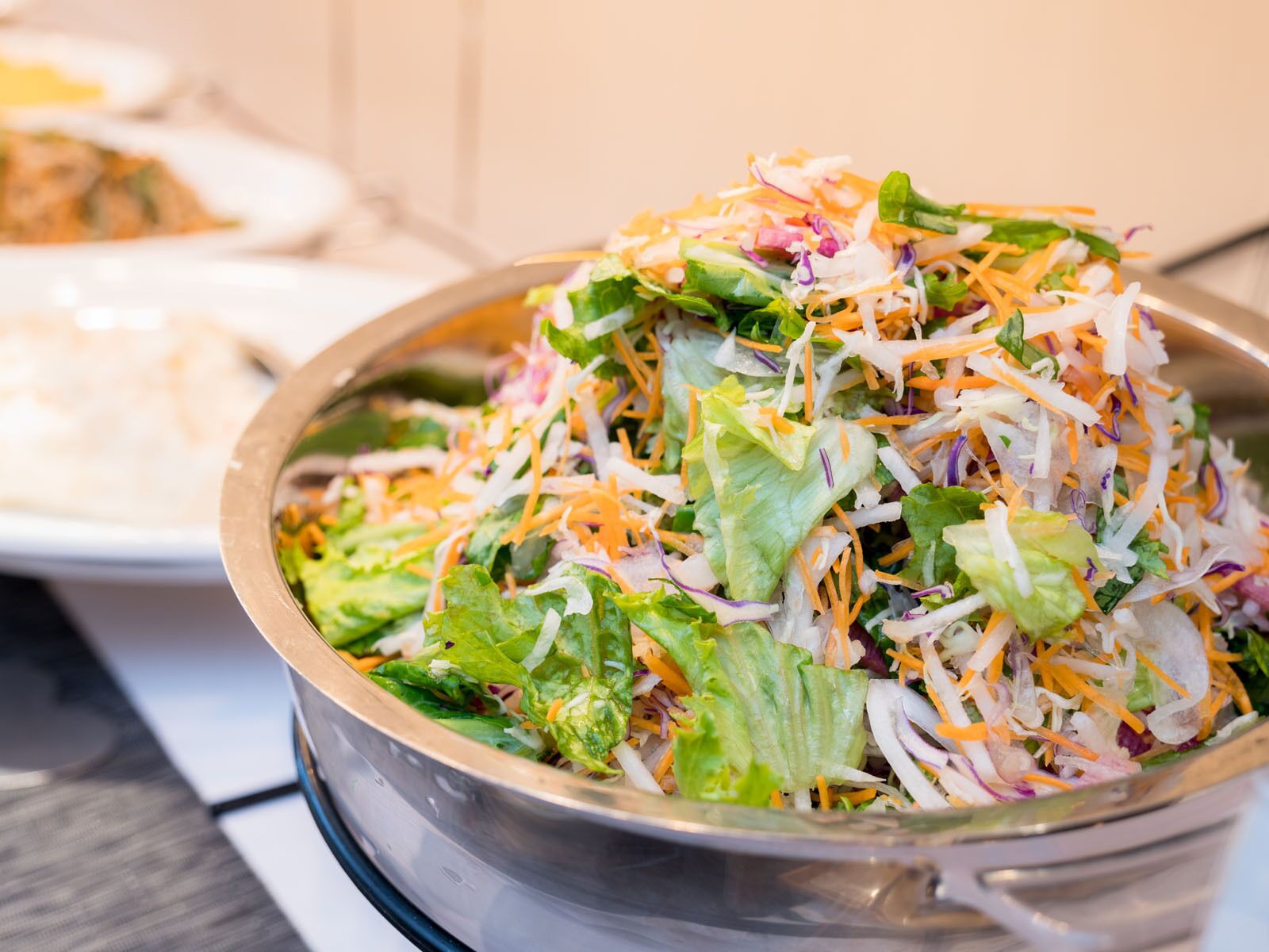 A bowl of salad with various vegetables and shredded cheese.