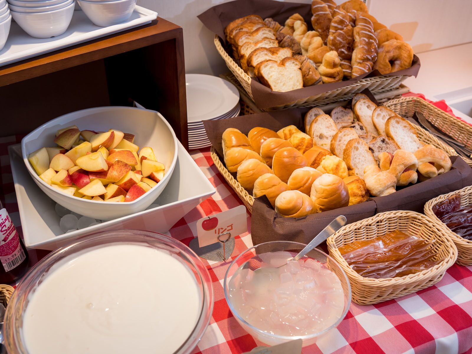 Un bufé con diversos alimentos, incluyendo pan, pasteles y un tazón de fruta.