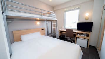 A compact hotel room with a bunk bed, a desk with a computer, a television, and a window with a city view.