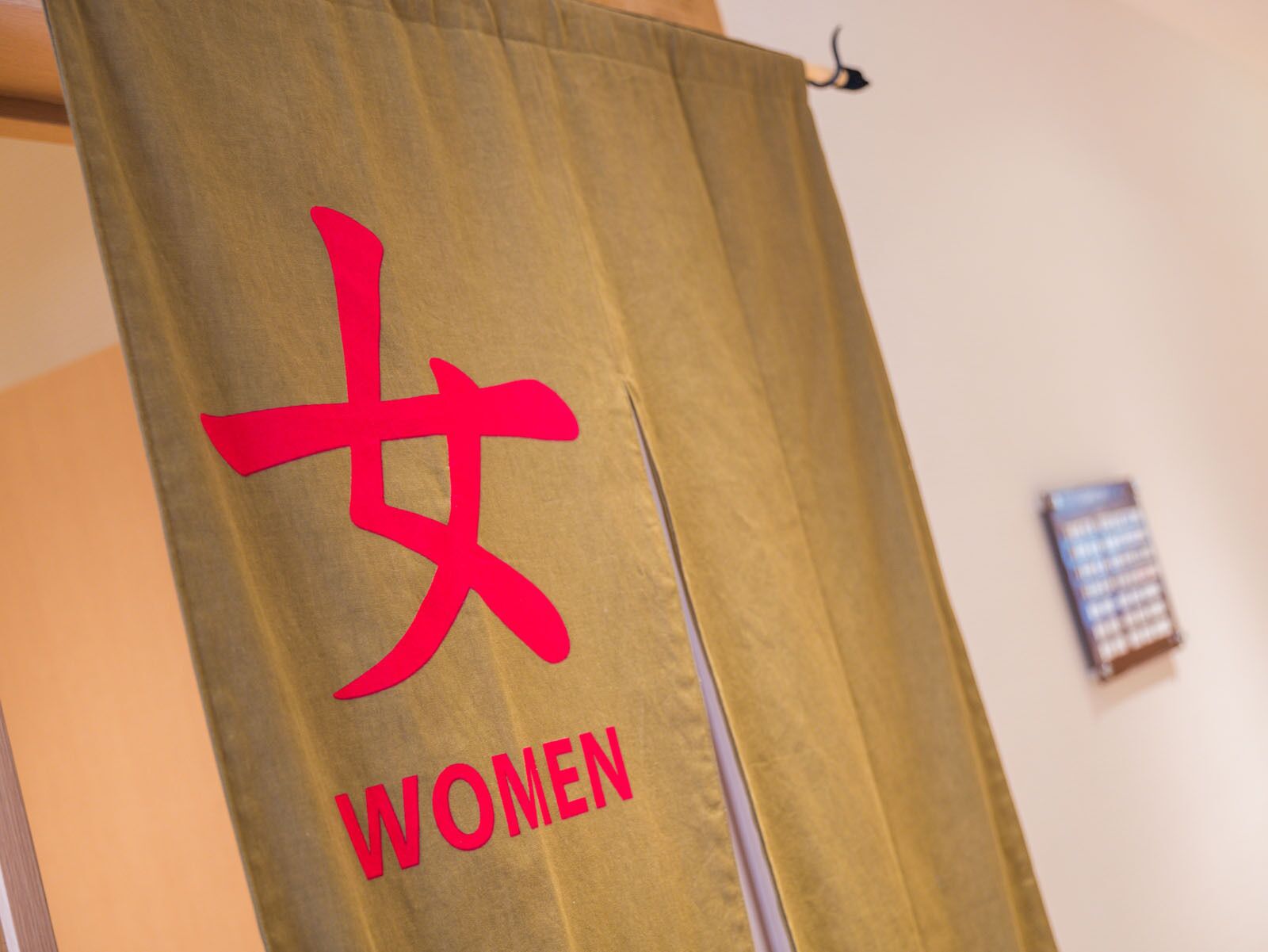 A room with a curtain displaying the word "WOMEN" in bold letters.