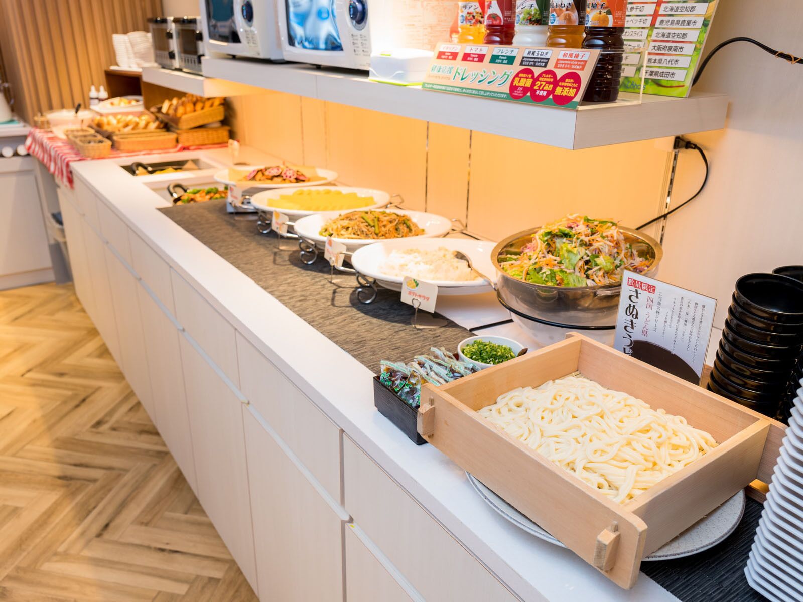 Una barra de buffet con diversos platos, como pasta, ensaladas y otros alimentos ya preparados.
