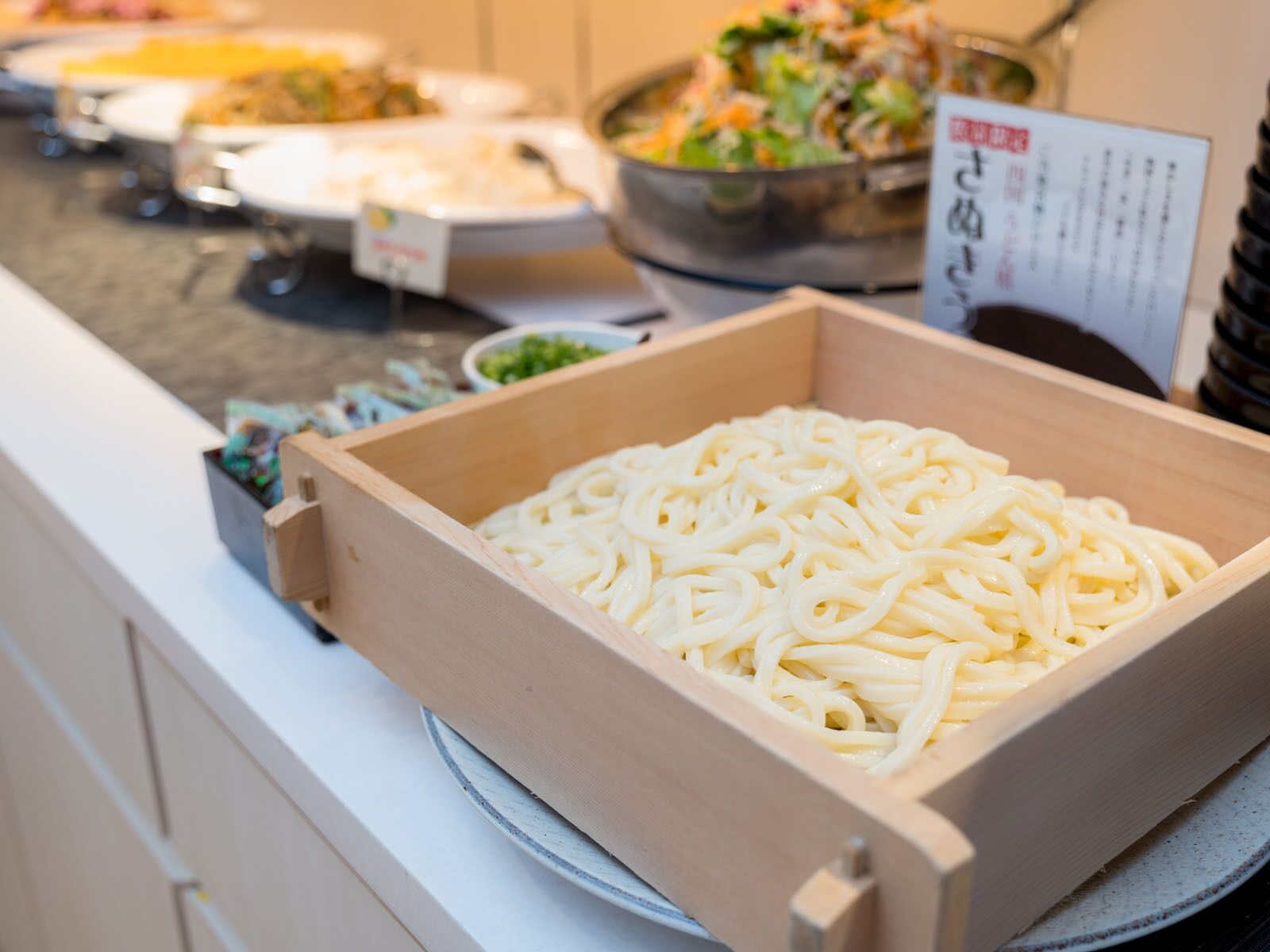 Uma caixa de madeira cheia de macarrão branco sobre uma mesa.