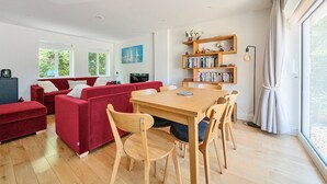 A modern living room with red sofas, a wooden dining table, and a bookshelf. - ★ Luxury Oxford Apartment ★ Sleeps 4, Free Parking - Pass the Keys (Oxford)