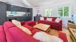 A modern living room with red sofas, a wooden coffee table, and a kitchen area with dark cabinetry. - ★ Luxury Oxford Apartment ★ Sleeps 4, Free Parking - Pass the Keys (Oxford)
