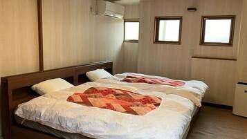 A room with two beds, wooden headboards, a window, and an air conditioning unit.