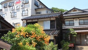 A traditional Japanese building with a wooden facade, a tiled roof, and a sign with Japanese characters. - Minsyuku Yodoya (Toyooka)