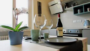 A dining table with a potted orchid, two wine glasses, a wine bottle, and a plate. - VINHOME -Your WINEderful stay in Alba. Apartment in the center of Alba (Alba)