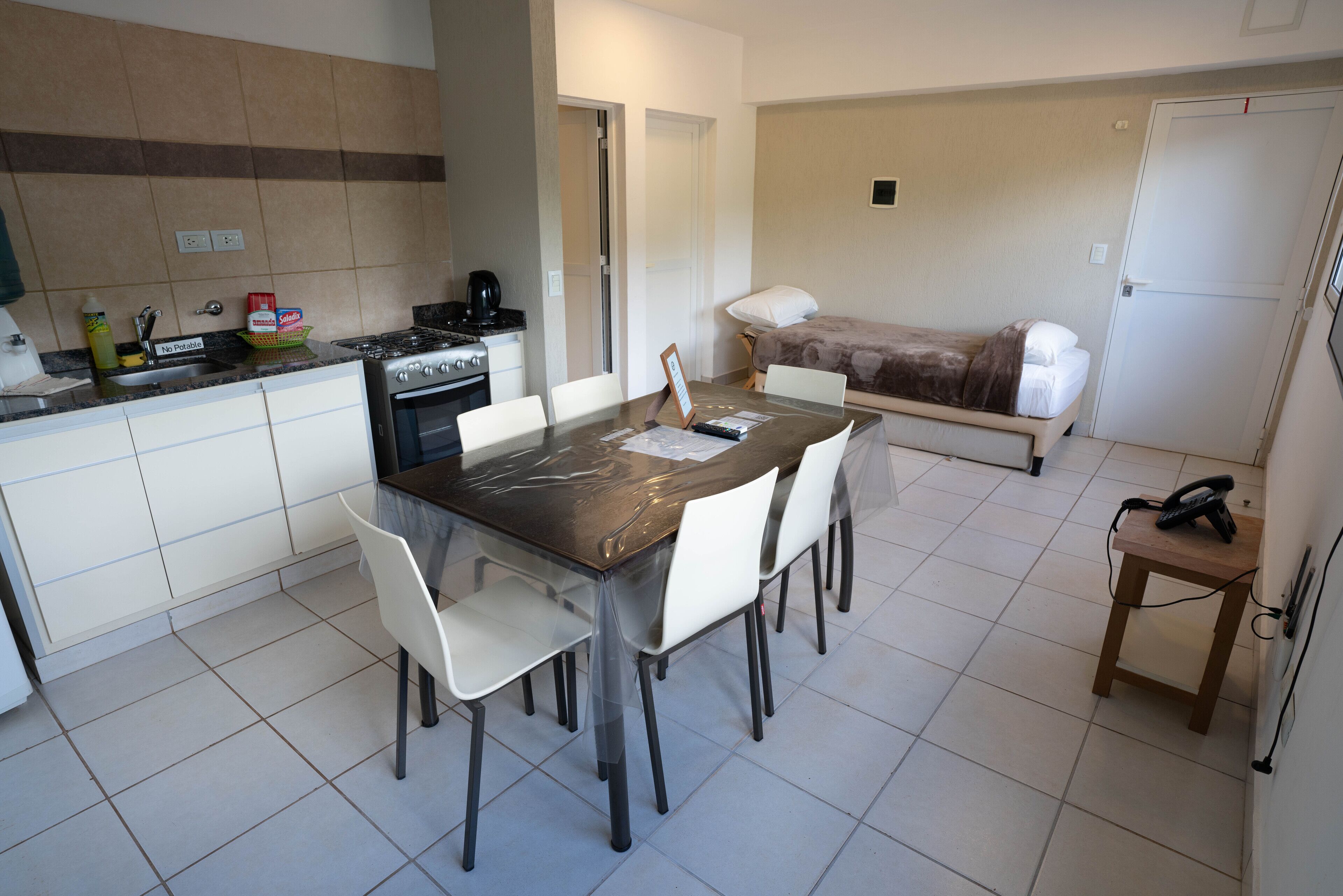 Una cocina compacta con una mesa, sillas, estufa y refrigerador.