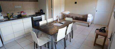 Una cocina compacta con una mesa, sillas, estufa y refrigerador.