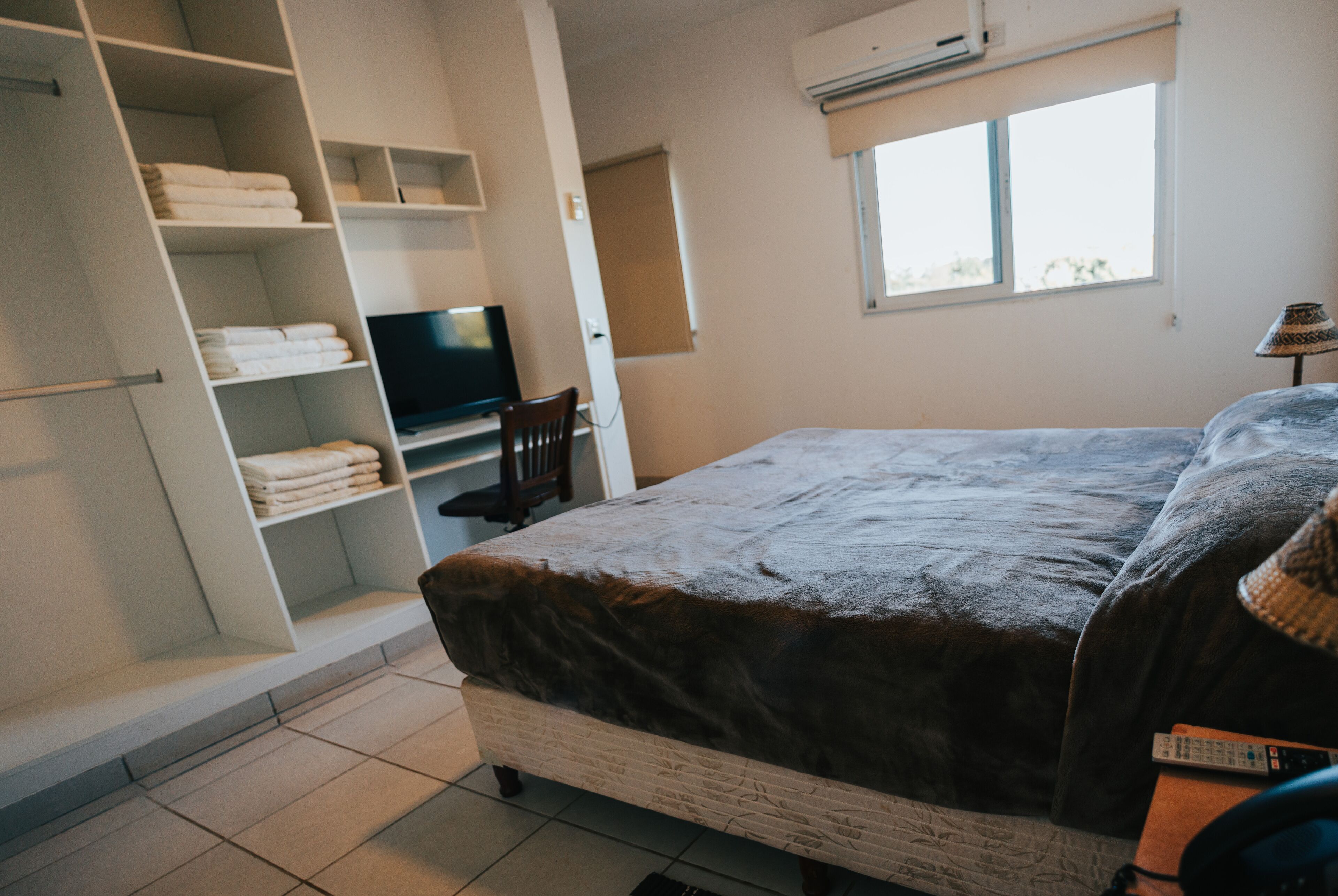 Une chambre à coucher avec un lit, une télévision et une armoire.