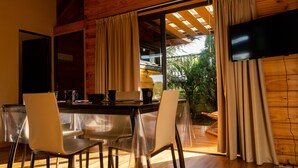 Un comedor con techo de madera, una mesa con sillas y vistas al exterior a través de amplios ventanales.