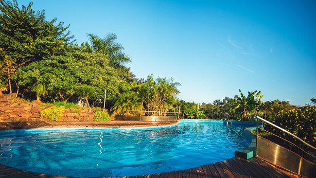 Una piscina con muelle de madera, rodeada de abundante vegetación y rocas.