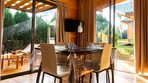 Un comedor con una mesa de vidrio, sillas y un televisor instalado en la pared.