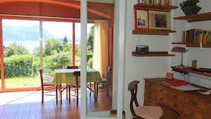 Een kamer met een eethoek, een bureau met boekenkasten en uitzicht op groen en bergen.
