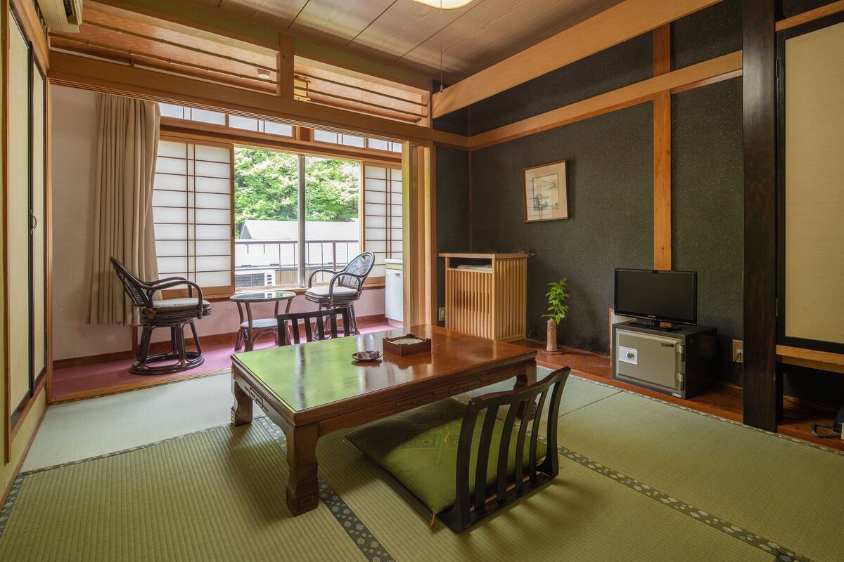 A traditional Japanese room with tatami flooring, a low table, and a television.