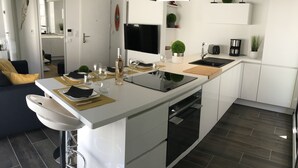 A modern kitchen with a central island, built-in oven, and a dining area with a bar stool. - Appt NEW Arcachon Center, Beach 250 m - Terrace - Private car park (Arcachon)
